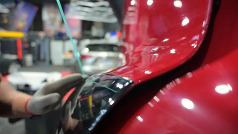 Process of applying a PPF film to a car. Worker removes the rest of PPF film Stock-Footage 294963673
