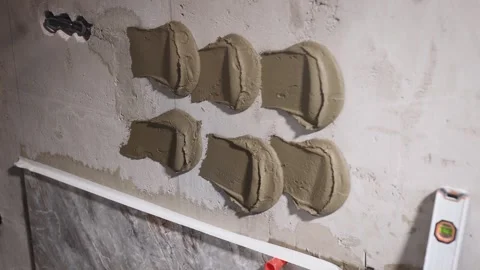 The process of applying tile adhesive to the wall. Surface preparation before Stock Footage 240903110