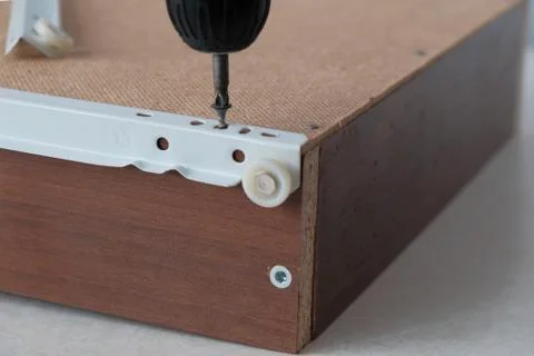 Process of assembling furniture, installing roller guides using  cordless scr Foto stock