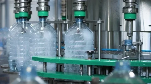 The process of automatic filling of water into a plastic bottle on filling unit Stock Footage 213848648