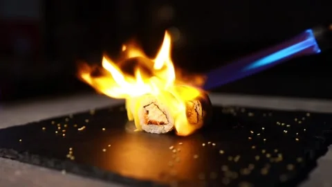 The process of baking Japanese sushi lying on a black iron sheet surrounded by Видео 145195979