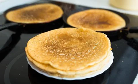 Process of baking pancakes in pans on kitchen stove. stack of hot pancakes Stock Photos