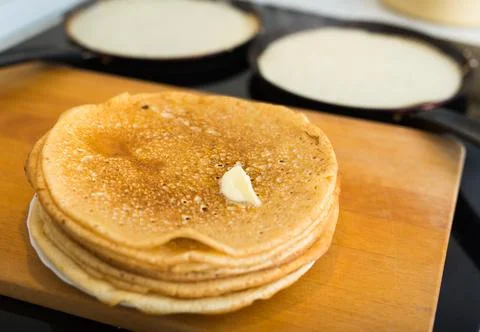 Process of baking pancakes in pans on kitchen stove. stack of hot pancakes Stock Photos