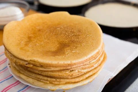 Process of baking pancakes in pans on kitchen stove. stack of hot pancakes Stock Photos