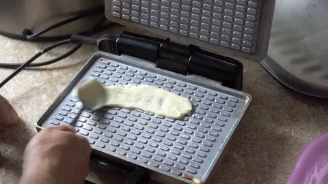 The process of baking waffles on an electric wafer, close-up. Woman smears the Stock Footage 102049670