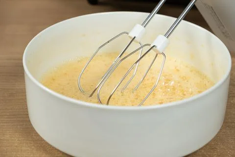 The process of beating eggs with sugar with a mixer, close-up, making the dough. Stock Photos