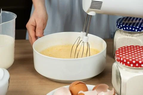 The process of beating eggs with sugar with a mixer, close-up, making the dough. Stock Photos