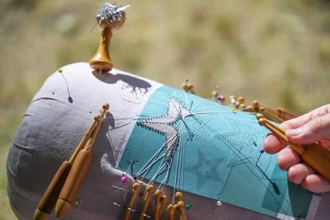 Process of bobbin lace in the shape of a star, hands manage the threads wi... Stock Photos