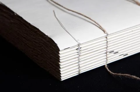 The process of book binding; close up of a raw book after sewing on cords. Stock Photos