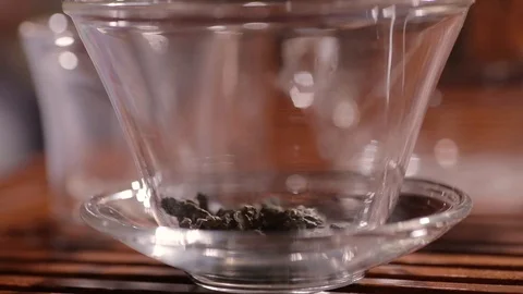 Process of brewing and unfolding fermented oolong tea leaves in glass gaiwan or Stock Footage 100336999
