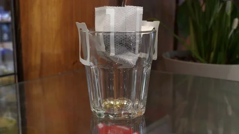The process of brewing black coffee with drip coffee bag in glass cup Stock Footage 161875486