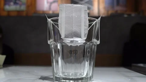 The process of brewing black coffee with drip coffee bag in glass cup Stock Footage 161875722