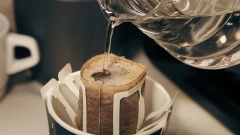 The process of brewing coffee. Water is poured into a drip coffee bag in a mug. Stock Footage 185569179