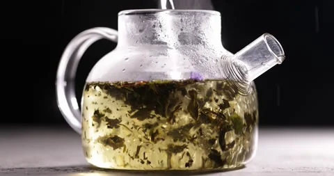 Process of brewing green tea in glass transparent teapot at dark background 스톡 동영상 172107799