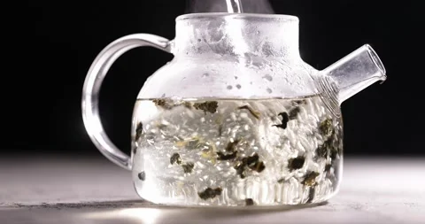 Process of brewing herbal tea in glass transparent teapot at dark background Stock-Footage 172107767