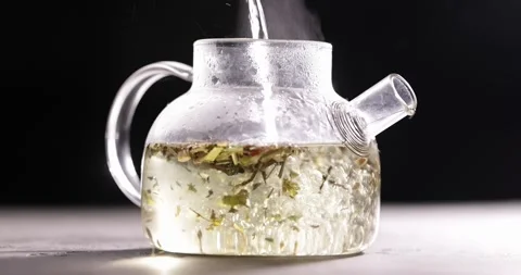 Process of brewing herbal tea in glass transparent teapot at dark background Stock Footage 172208611
