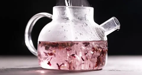 Process of brewing pink flowers tea in glass transparent teapot at dark Stock Footage 172208586