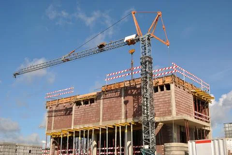 Process of building a house, work with a crane and blue sky in the background Stock Photos