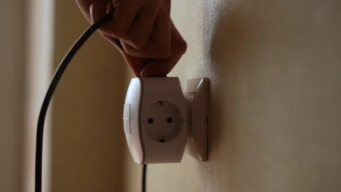 Process of careful insertion of black electrical plug into white wall socket Stock Footage 293370459