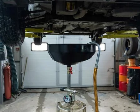 The process of changing the oil in a car engine. Draining old dark used oil from Stockfoto's