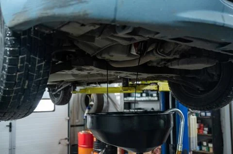 The process of changing the oil in a car engine. Draining old dark used oil from Stockfoto's