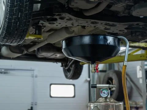 The process of changing the oil in a car engine. Draining old dark used oil from Stockfoto's