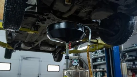 The process of changing the oil in a car engine. Draining old dark used oil from Foto stock