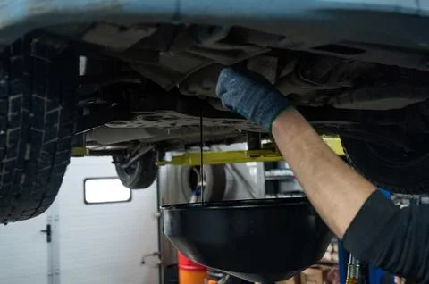 The process of changing the oil in a car engine. Draining old dark used oil from Foto stock