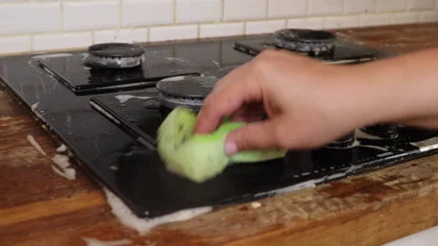 The process of cleaning a black stove in a home kitchen Stock Footage 282502780