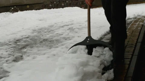 The process of cleaning snow from sidewalk and using snow shovel. Stock Footage 169007616