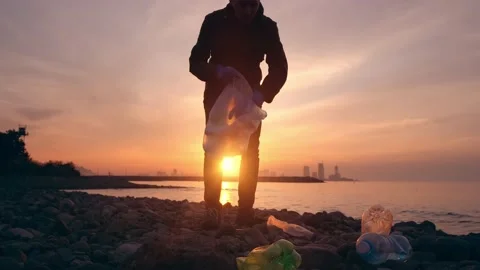 Process of cleaning stone beach from plastic waste. Man picks up plastic bottles Stock-Footage 231919586