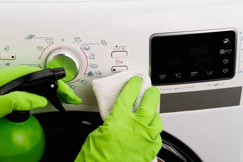 The process of cleaning a washing machine using a spray bottle and a wipe Фото