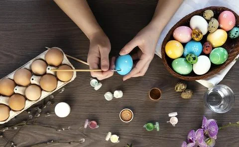 The process of coloring Easter eggs, female hands color eggs, top view. 库存照片