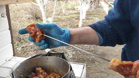 The process of cooking barbecue on a skewer, , a man puts meat on a skewer Stock Footage 170694130