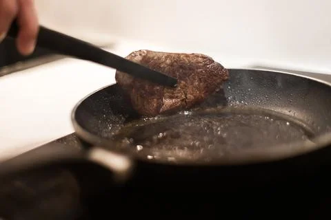 The process of cooking beef steak in a frying pan 写真素材