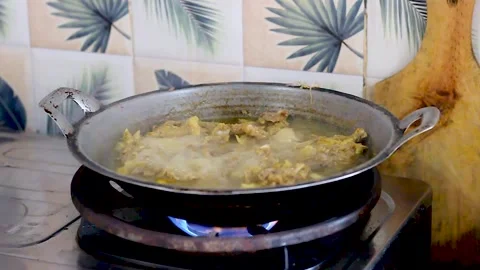 The process of cooking chicken stew using a cauldron Stock Footage 258808433