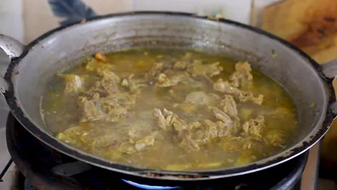 The process of cooking chicken stew using a cauldron Stock Footage 258808436