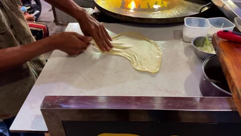 The process of cooking egg martabak. The dough material is stretched by Stock Footage 279231544