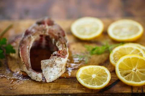 The process of cooking fish, fresh raw tasty piece of fish with lemon slices  Stock Photos