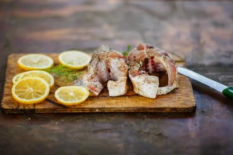 The process of cooking fish, two fresh raw tasty pieces of fish with lemon sl Stock Photos