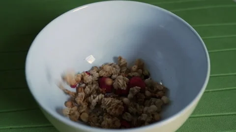 Process of cooking healthy dieting breakfast or snack. Pours muesli into a ce Stock Footage 152186183