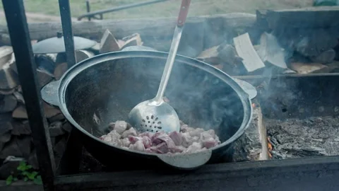 Process of cooking lamb for pilaf in cauldron on open fire Stock Footage 247436337