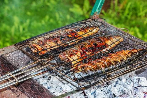 The process of cooking mackerel fish in a marinade on the grill. The fish is  Stock Photos