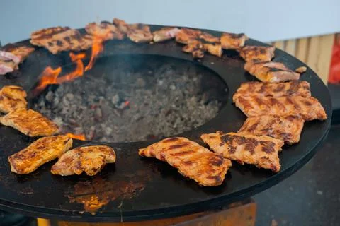 Process of cooking meat steaks on round brazier - close up Stock Photos