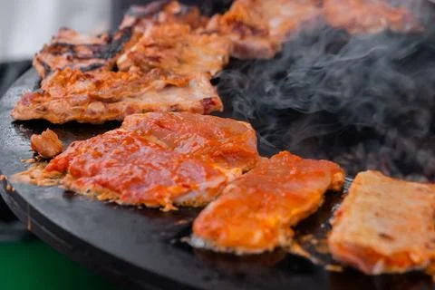 Process of cooking meat steaks on round brazier - close up Stock Photos