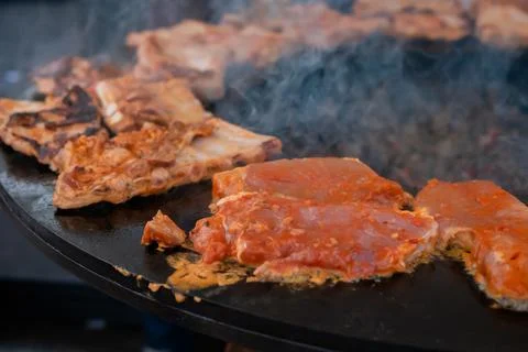 Process of cooking meat steaks on round brazier - close up Stock Photos