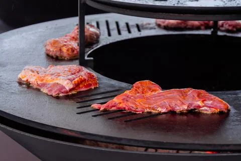Process of cooking meat steaks on round brazier - close up Stock Photos
