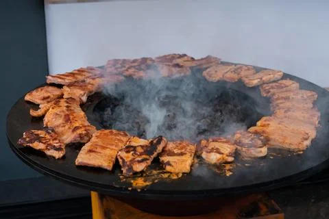 Process of cooking meat steaks on round brazier - close up Stock Photos