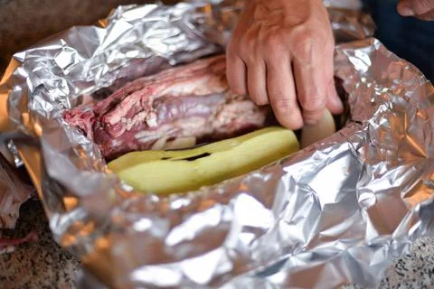The process of cooking meat with vegetables wrapped in foil, on the grill at  Stock Photos