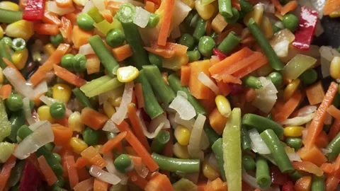 The process of cooking multicolored sliced vegetables in a frying pan Stock Footage 277969144
